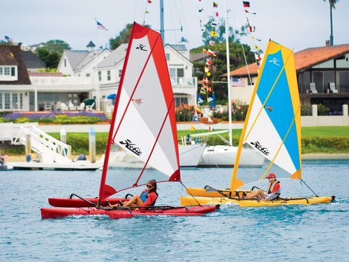 Two people are sailing kayaks on a body of water.