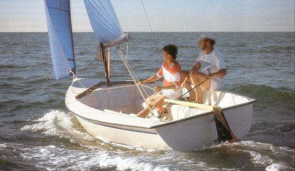 Two people are sailing a small boat in the ocean.