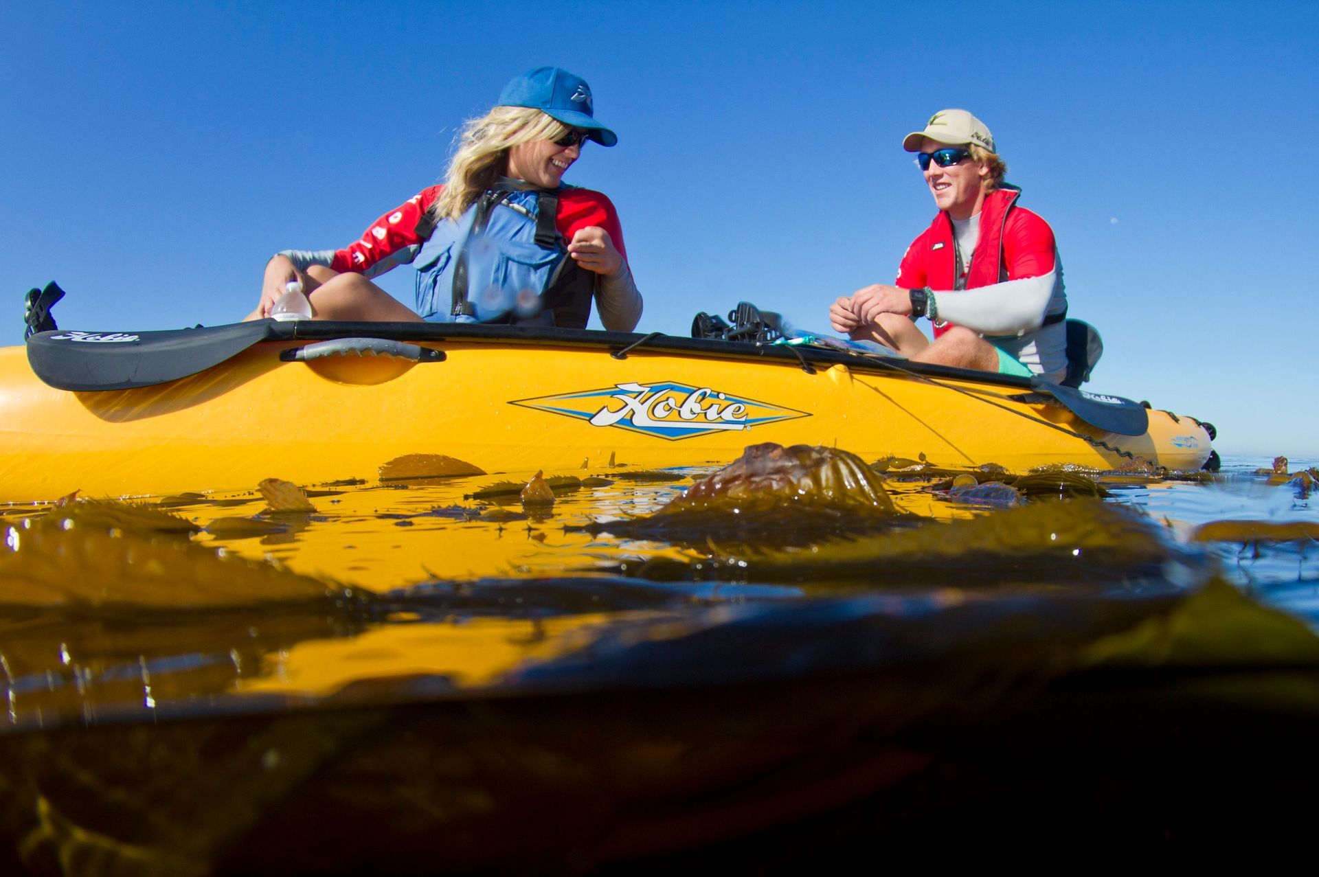 Two people are sitting in a yellow kayak in the water.