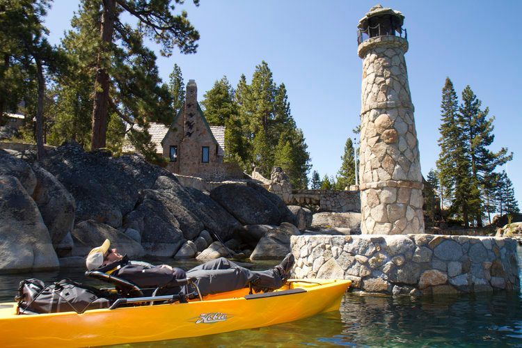 A man is laying in a yellow kayak in front of a lighthouse