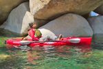 A person is sitting in a red kayak in the water.