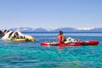 A man is riding a red kayak in the water.
