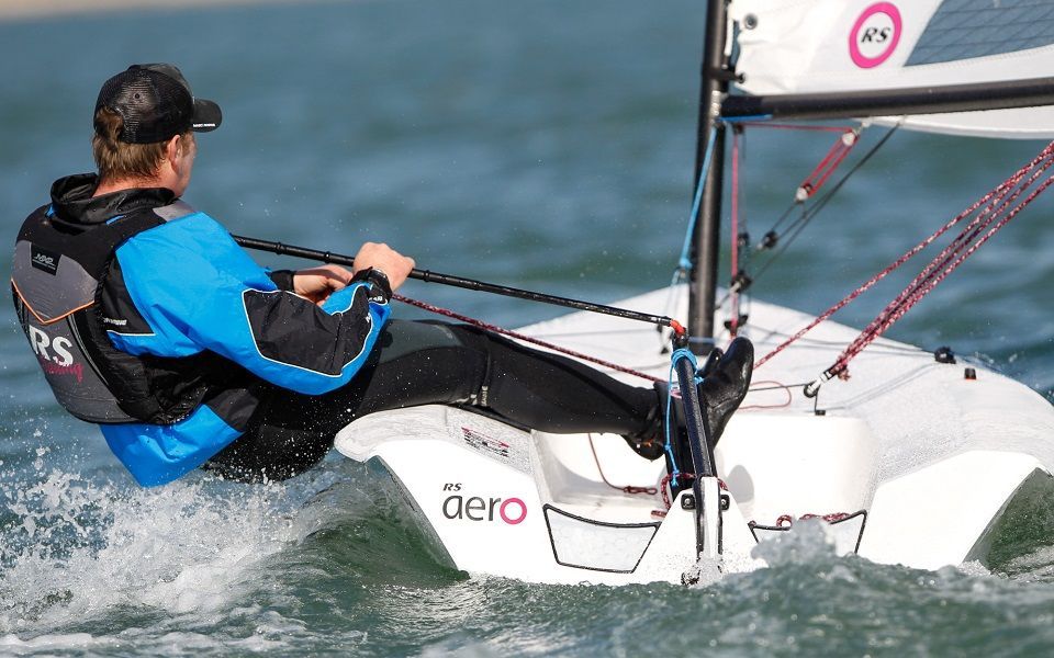 A man is sailing a dero sailboat in the ocean