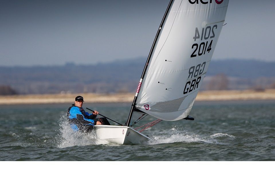 A man is sailing a small sailboat in the ocean.