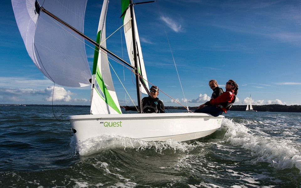 Two people are sailing a small sailboat in the ocean.