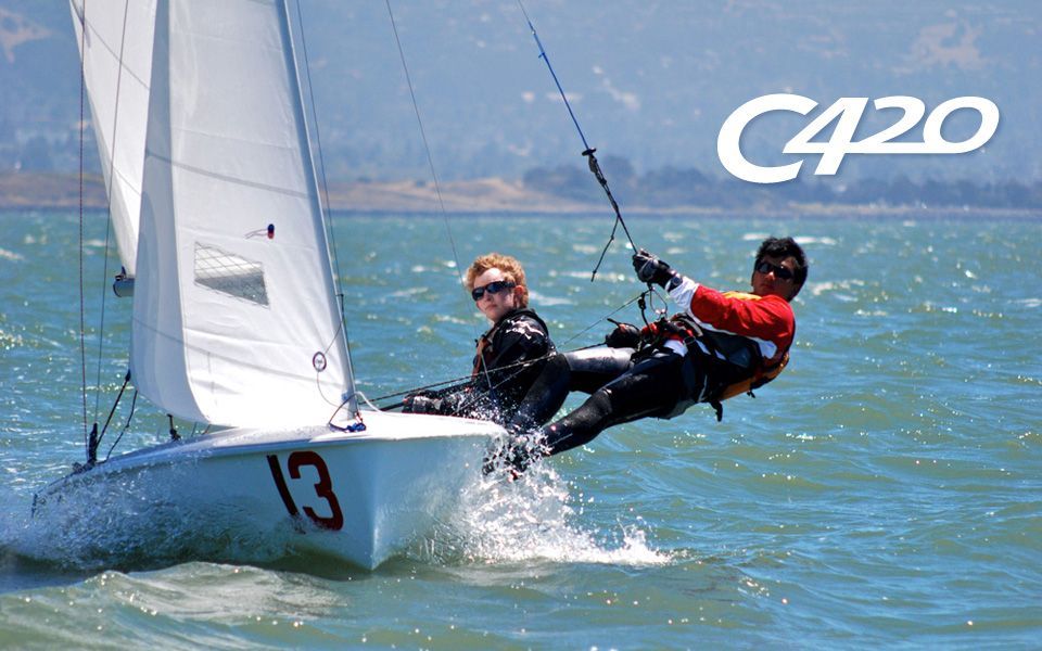 Two people are sailing a boat with the number 13 on it