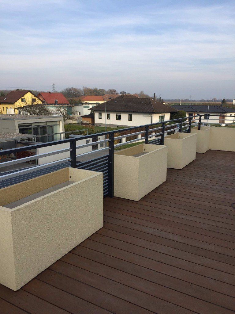 Ein Balkon mit Pflanzkübeln und Blick auf die Stadt