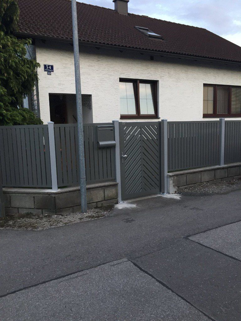 Ein weißes Haus mit einem Zaun und einem Tor davor