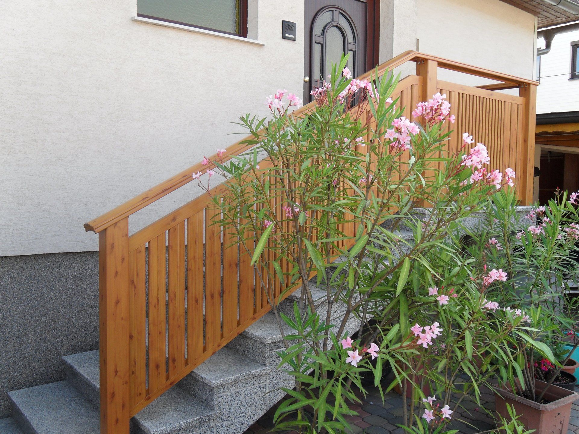 Eine Treppe mit einem Holzgeländer und rosa Blumen