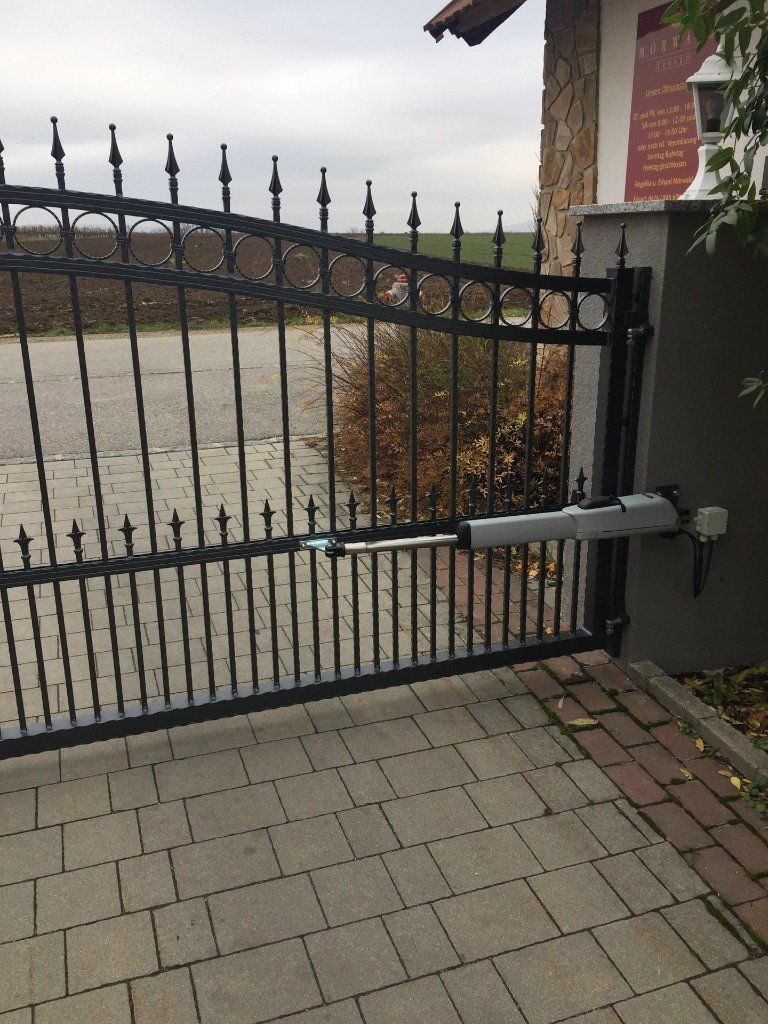 Ein schmiedeeisernes Tor führt zu einer gemauerten Auffahrt