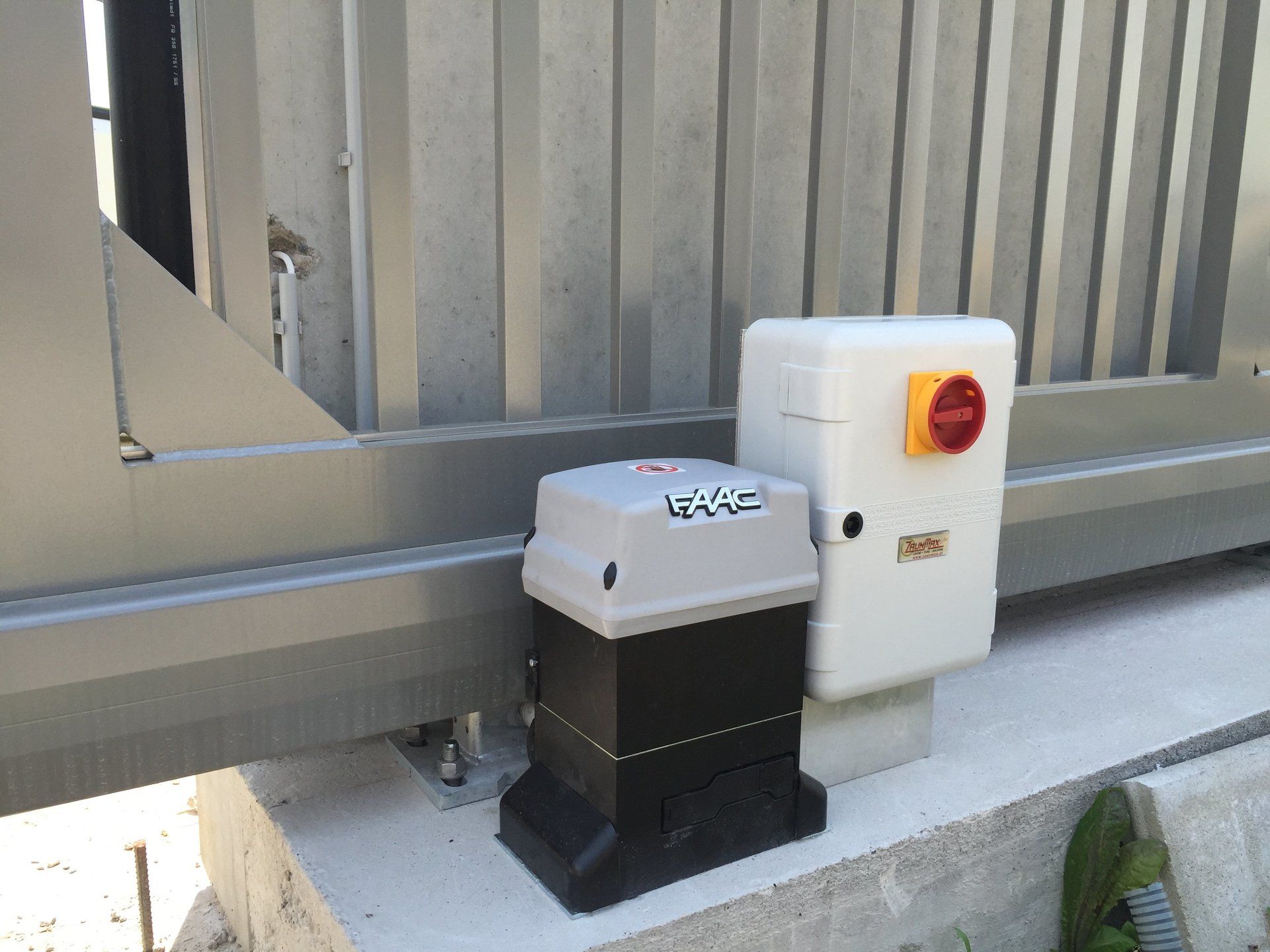 Neben einem Schiebetor sitzt ein Schiebetormotor.