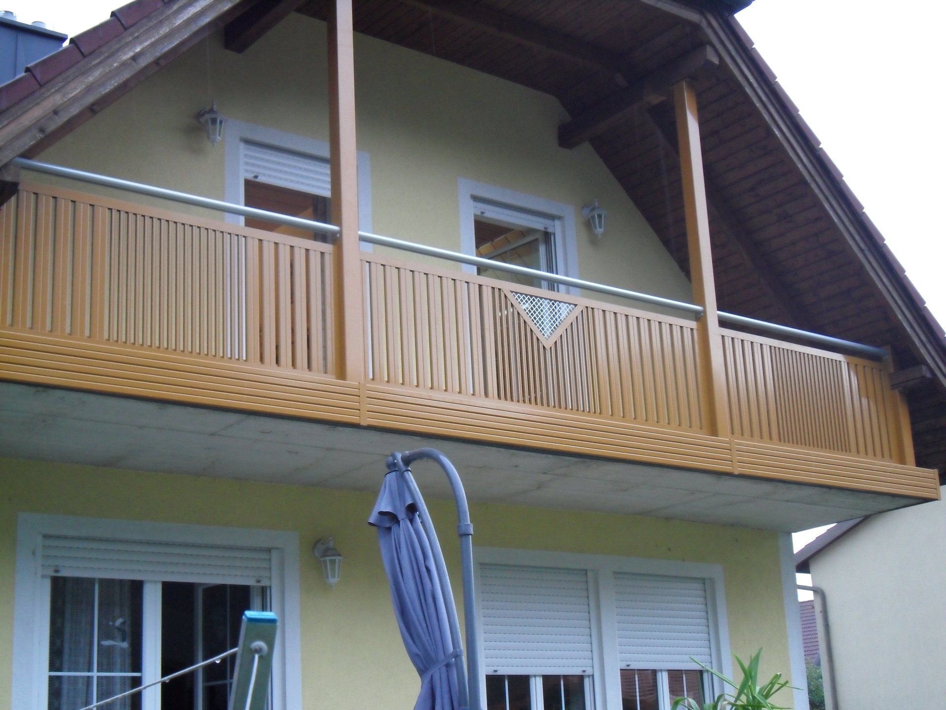 Ein gelbes Haus mit Balkon und blauem Sonnenschirm
