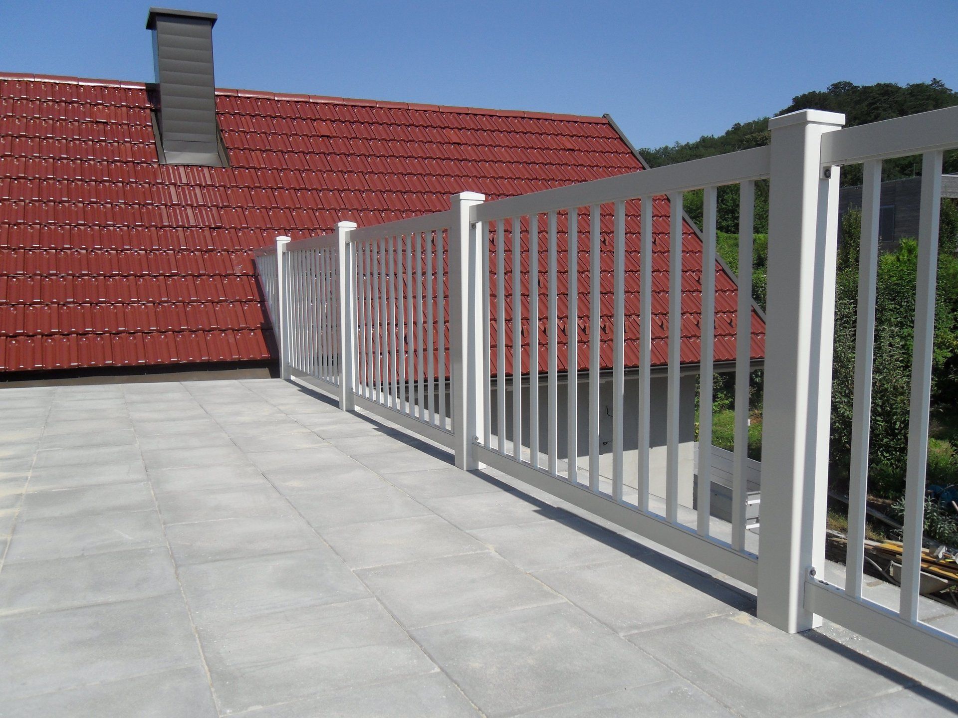 Ein Balkon mit weißem Geländer und rotem Dach