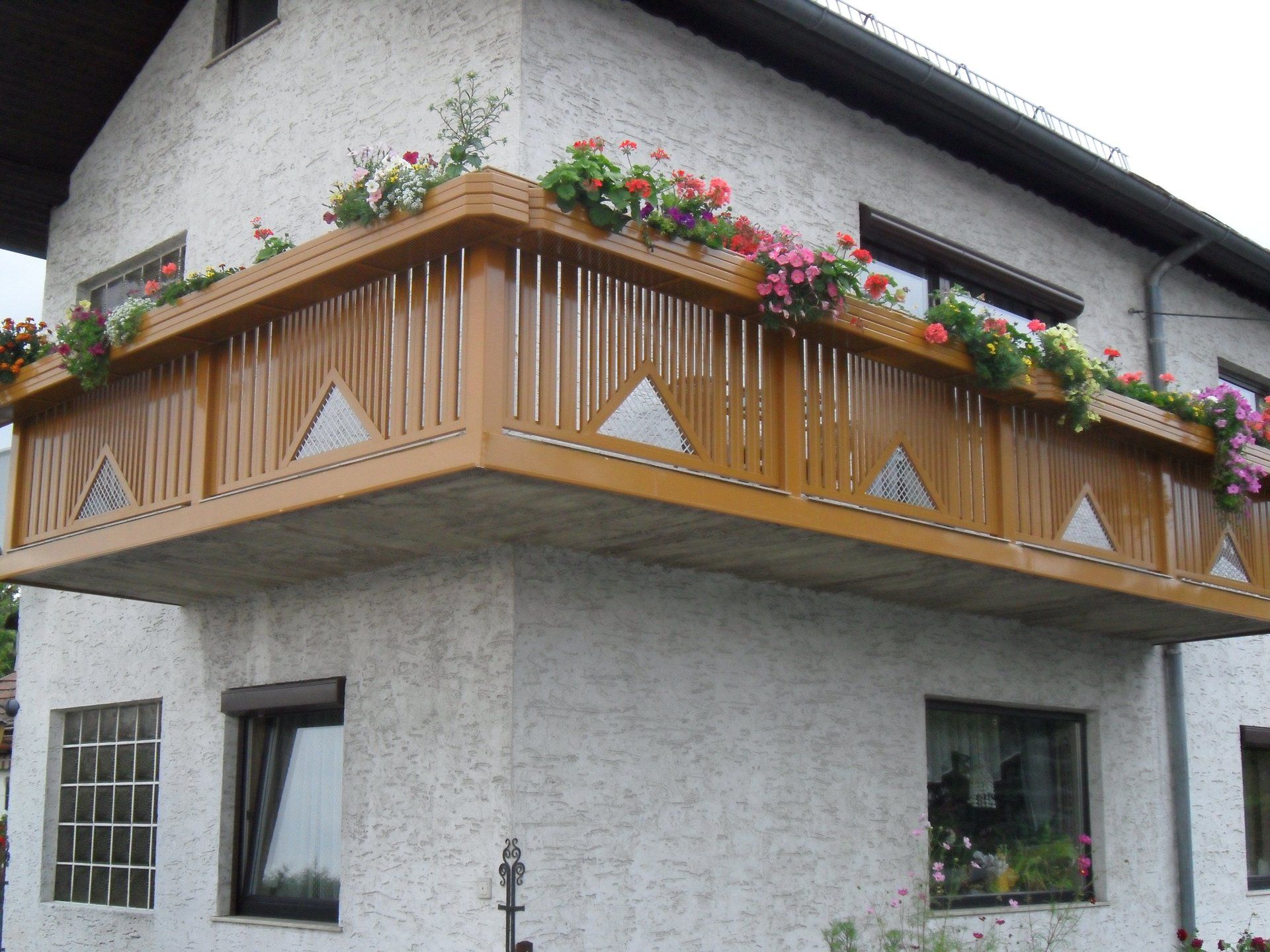 Ein Haus mit einem Balkon mit Blumen darauf