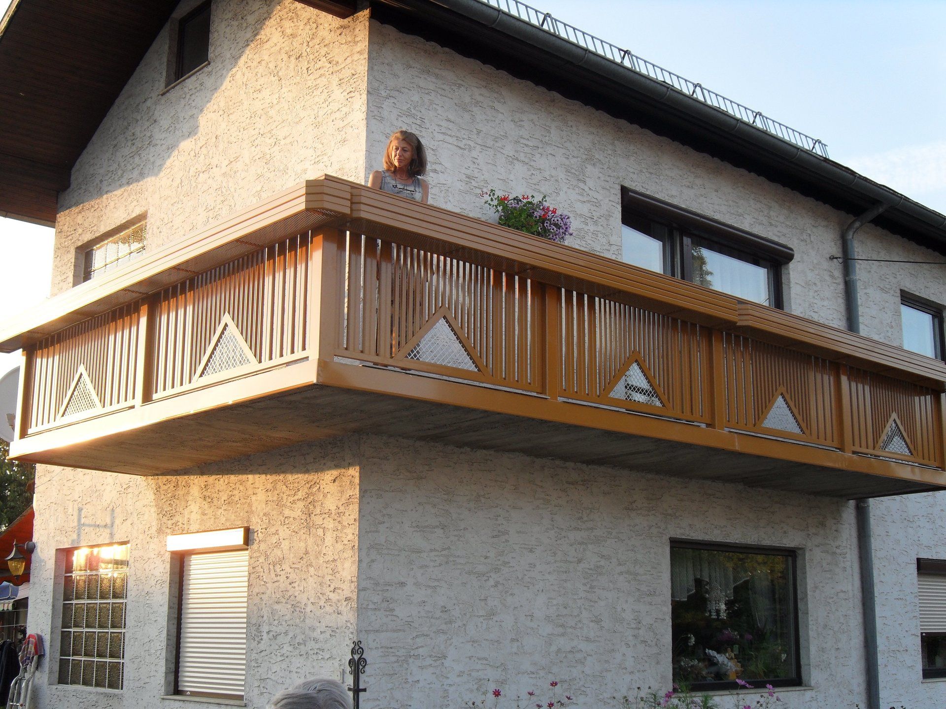 Eine Frau sitzt auf einem Balkon eines Hauses