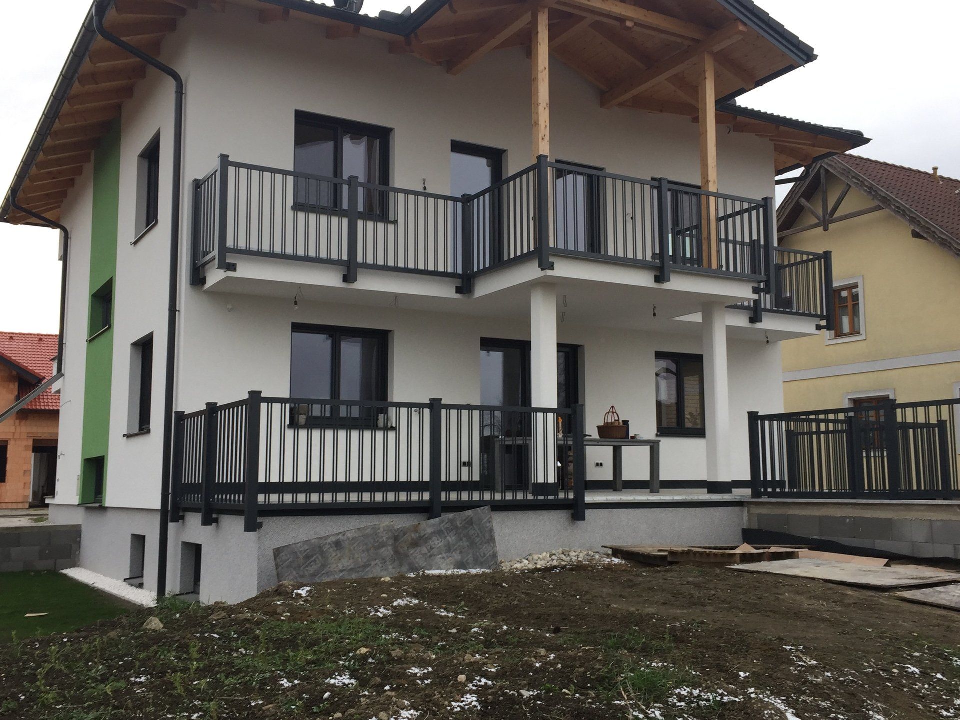 Ein weißes Haus mit einem Balkon und einem schwarzen Geländer