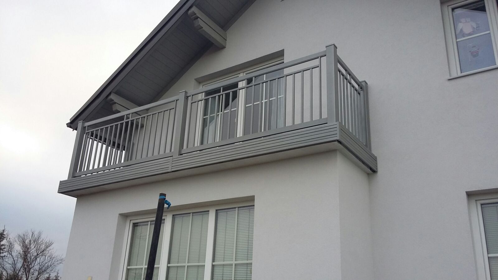 Ein weißes Haus mit einem Balkon an der Seite.