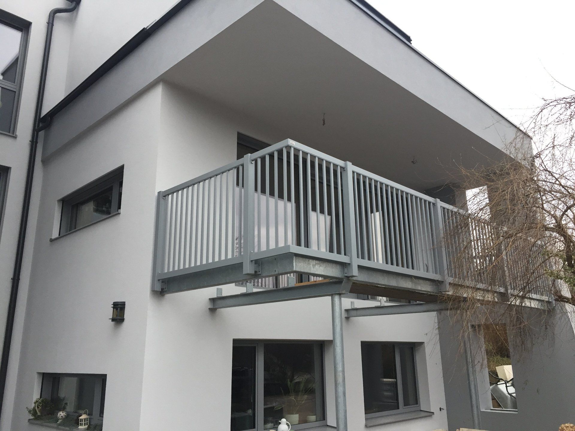 Ein weißes Haus mit einem Balkon an der Seite.