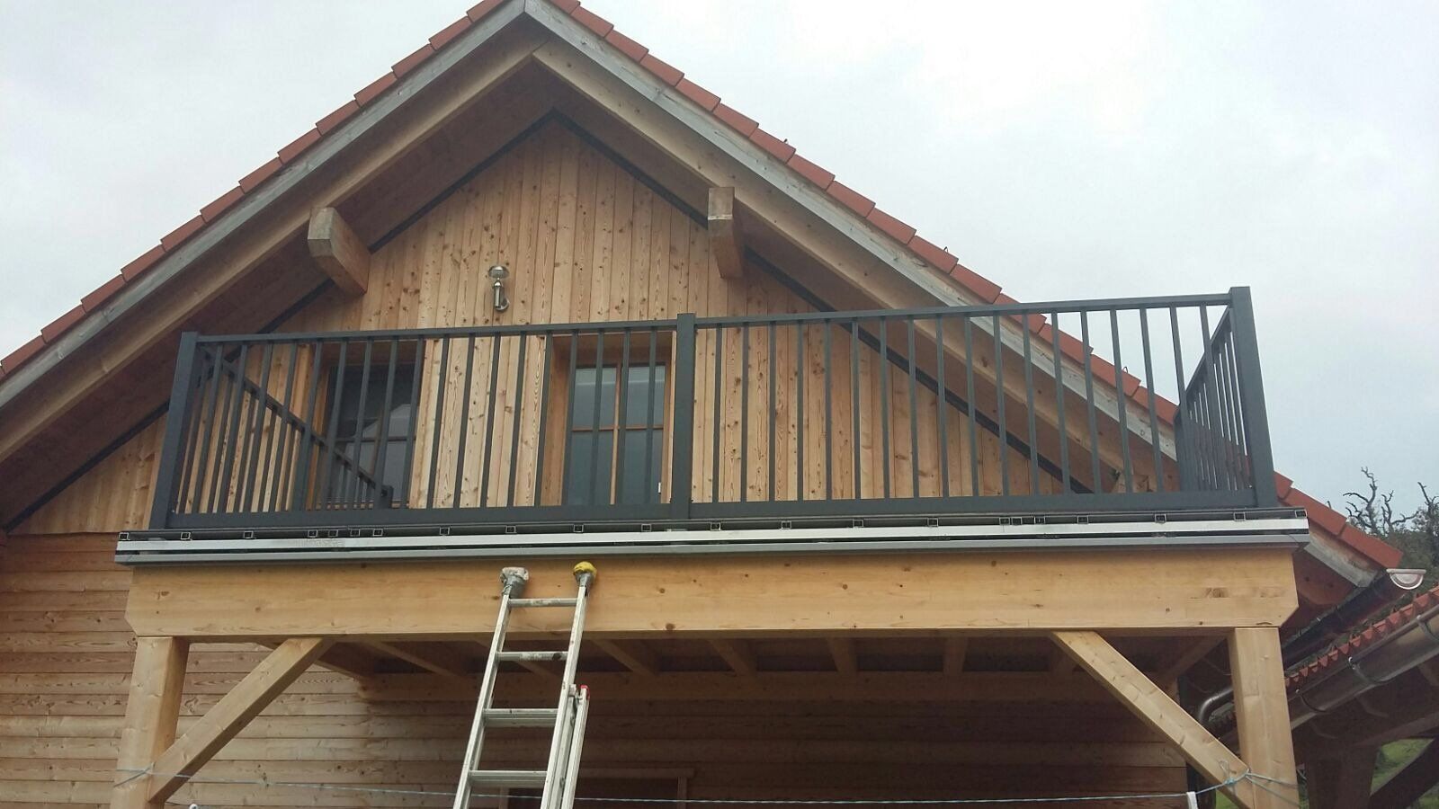 Ein Holzhaus mit einem Balkon und einer Leiter darauf.