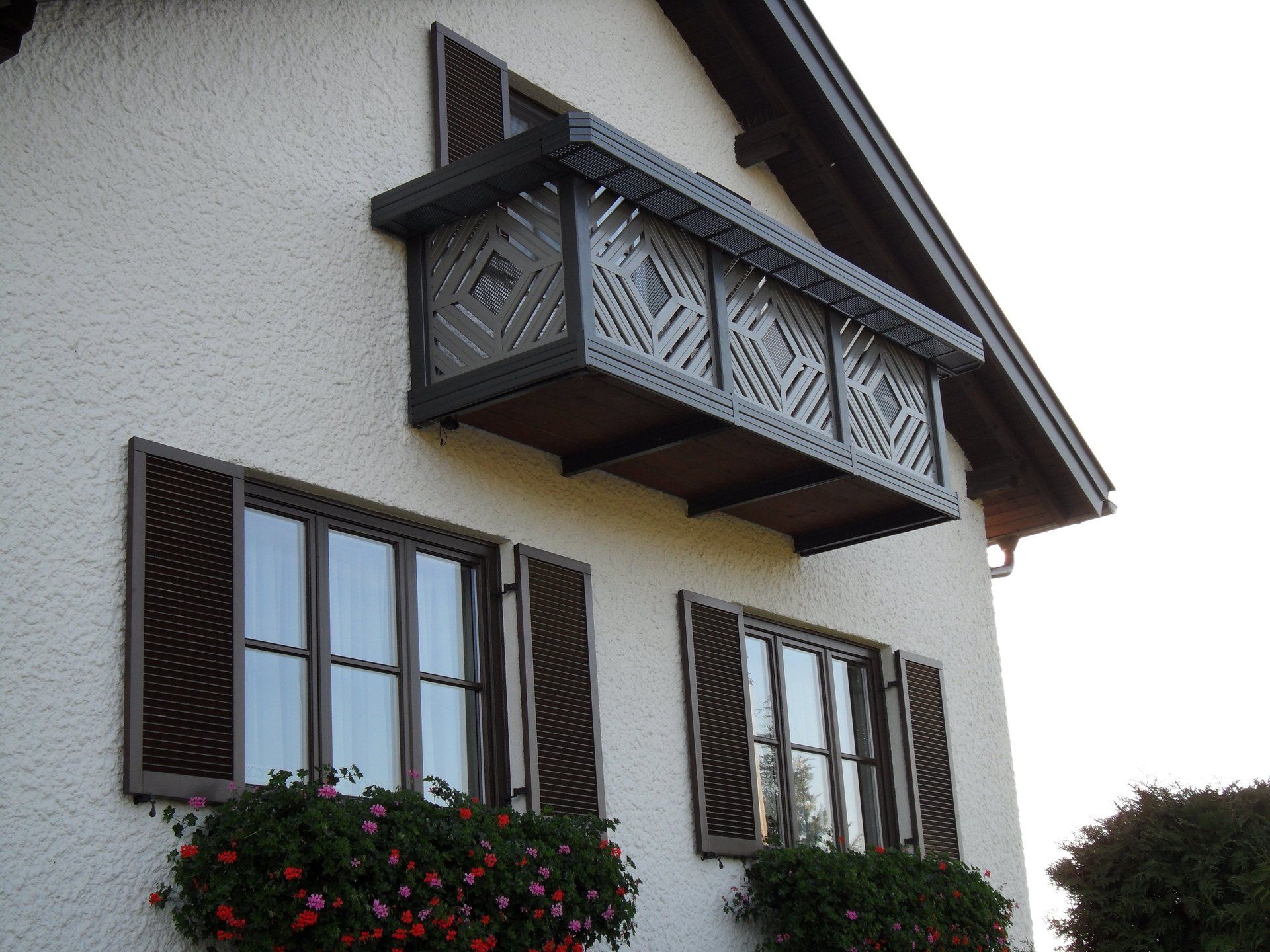Ein weißes Haus mit Balkon und Blumen an den Fenstern
