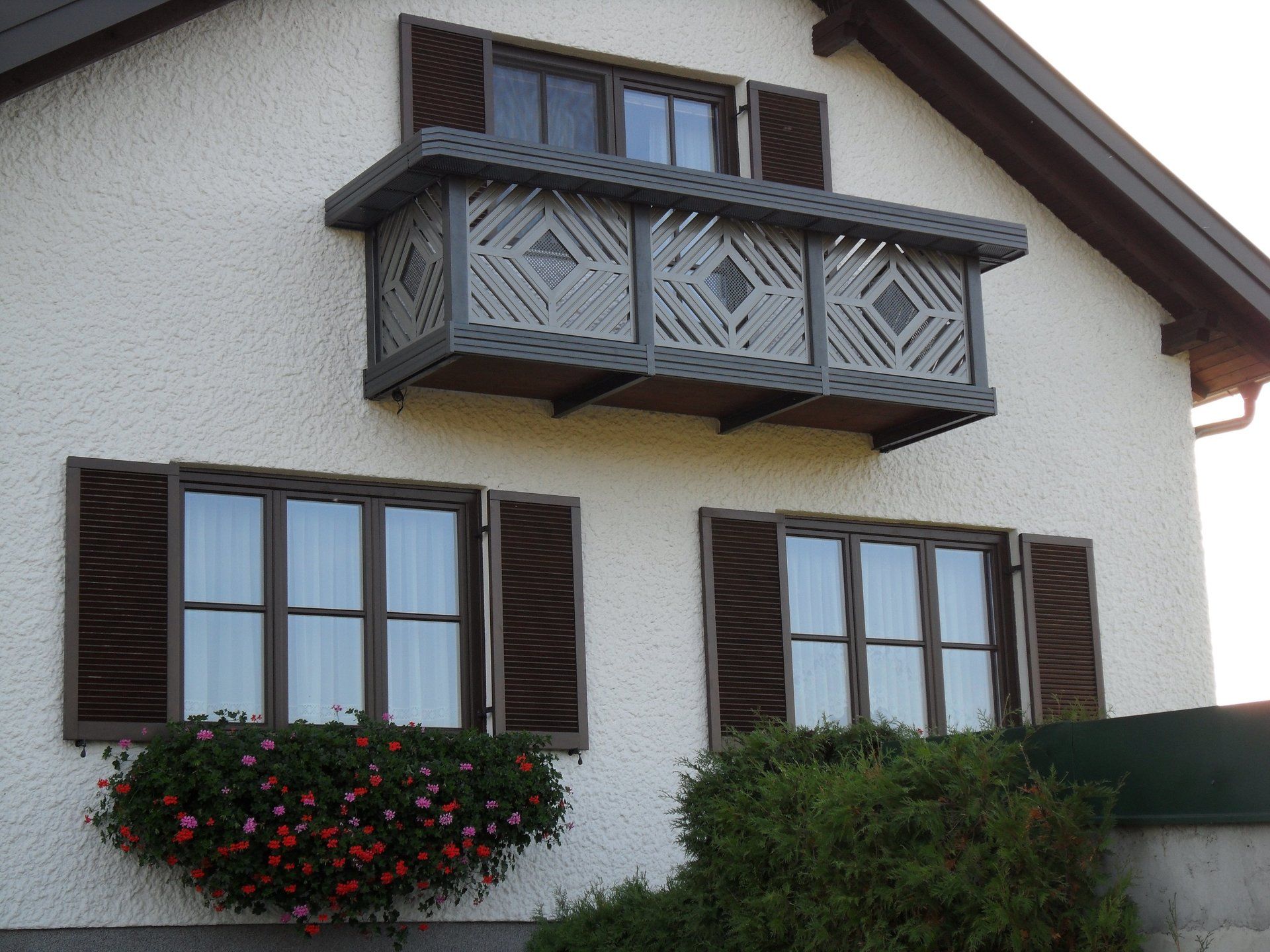 Ein weißes Haus mit braunen Fensterläden und einem Balkon