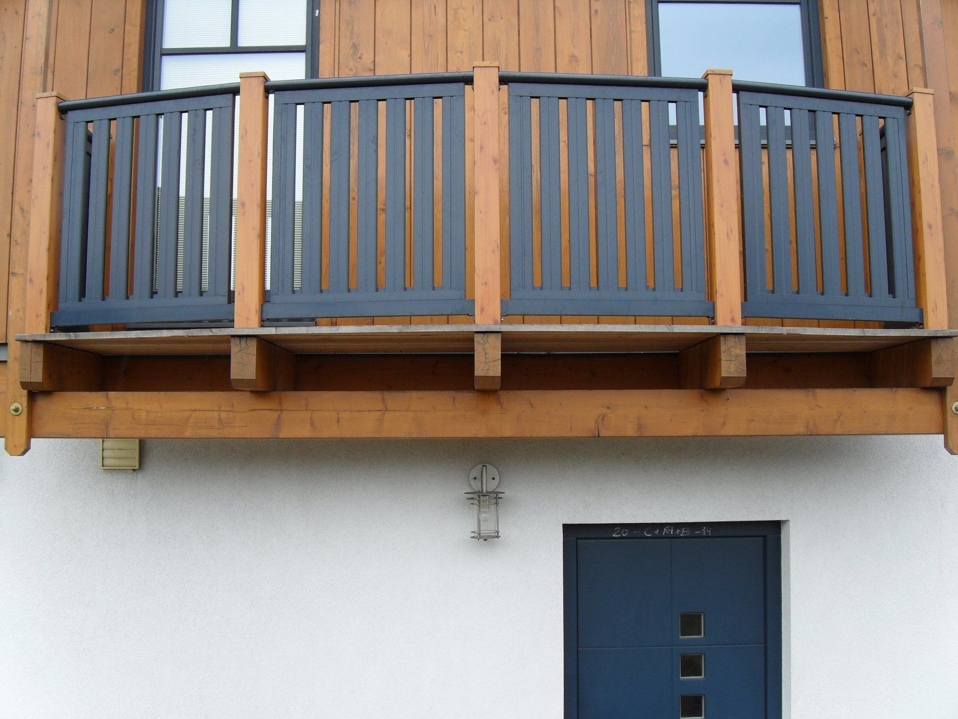 Ein Balkon an der Seite eines Hauses mit einem schwarzen Geländer