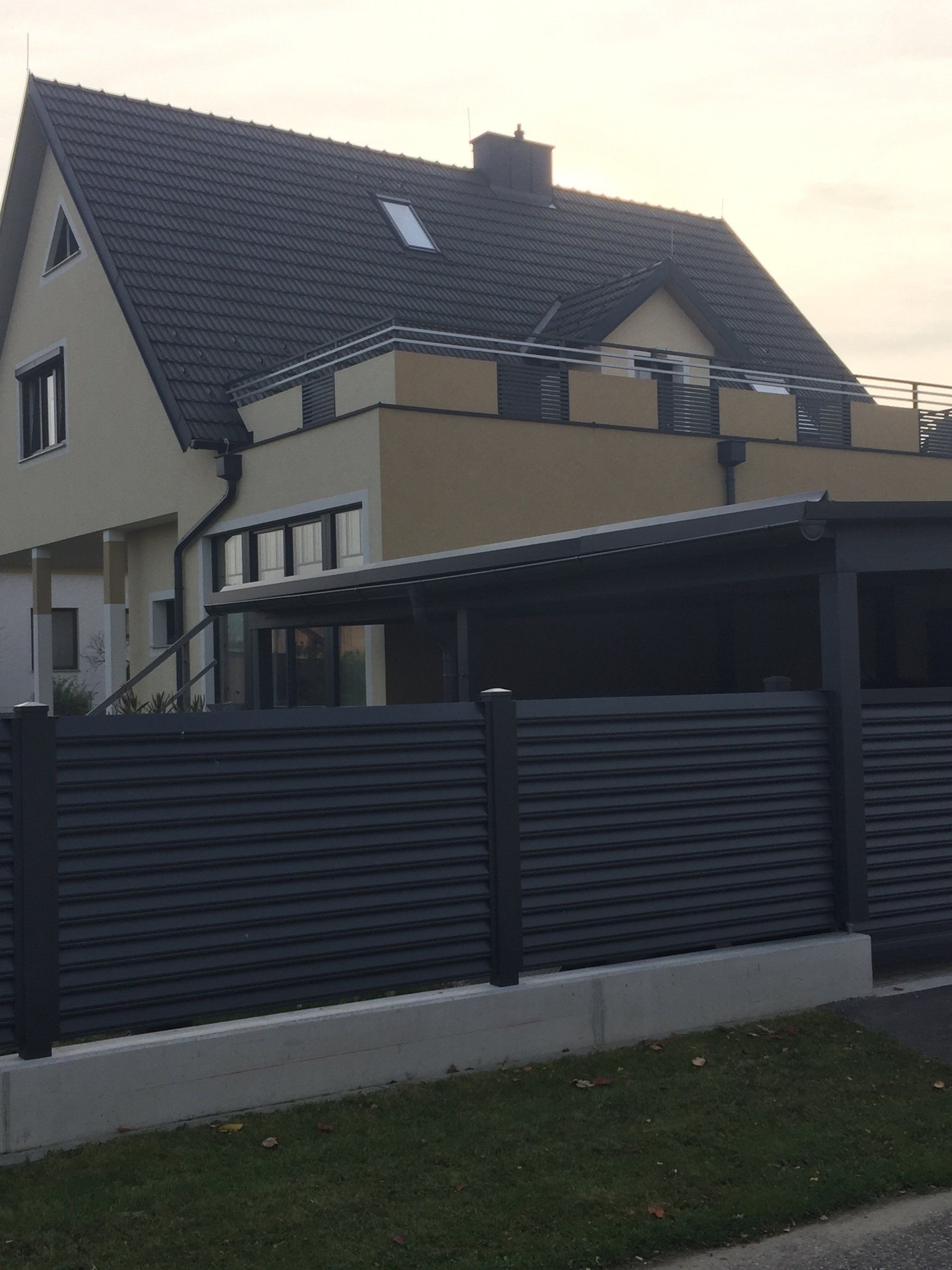 Ein großes Haus mit einem schwarzen Zaun davor.