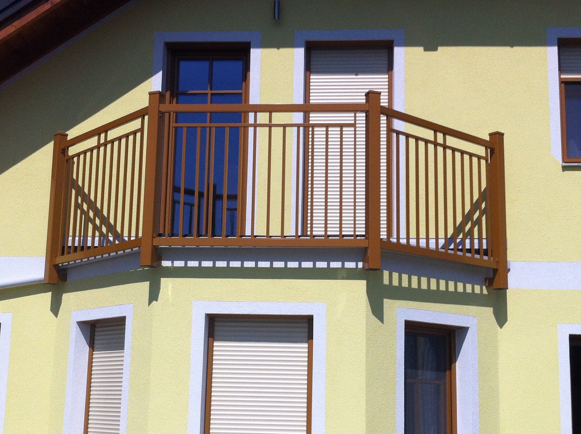 Ein gelbes Haus mit Balkon und Fensterläden