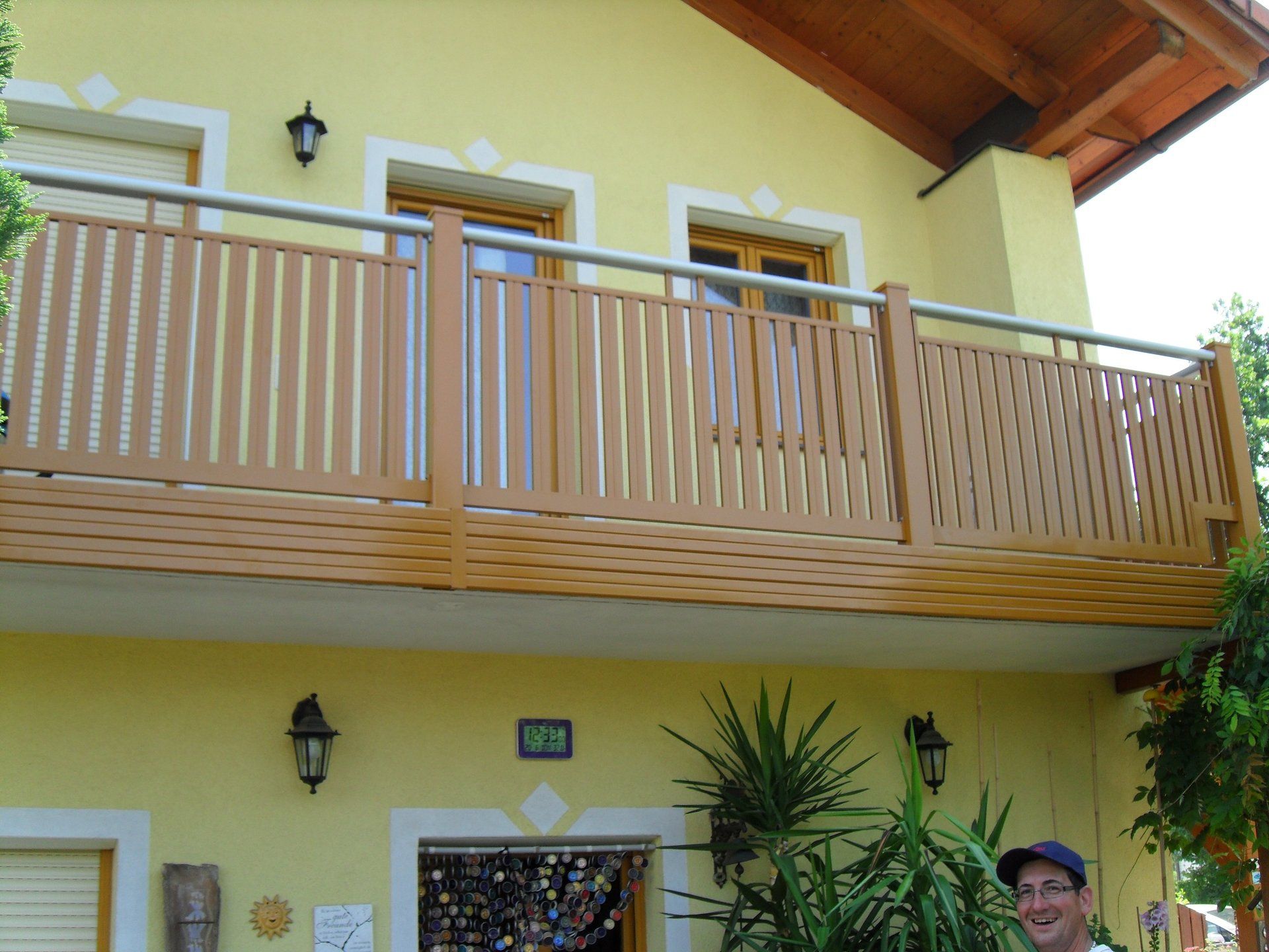 Ein Mann steht auf dem Balkon eines gelben Hauses