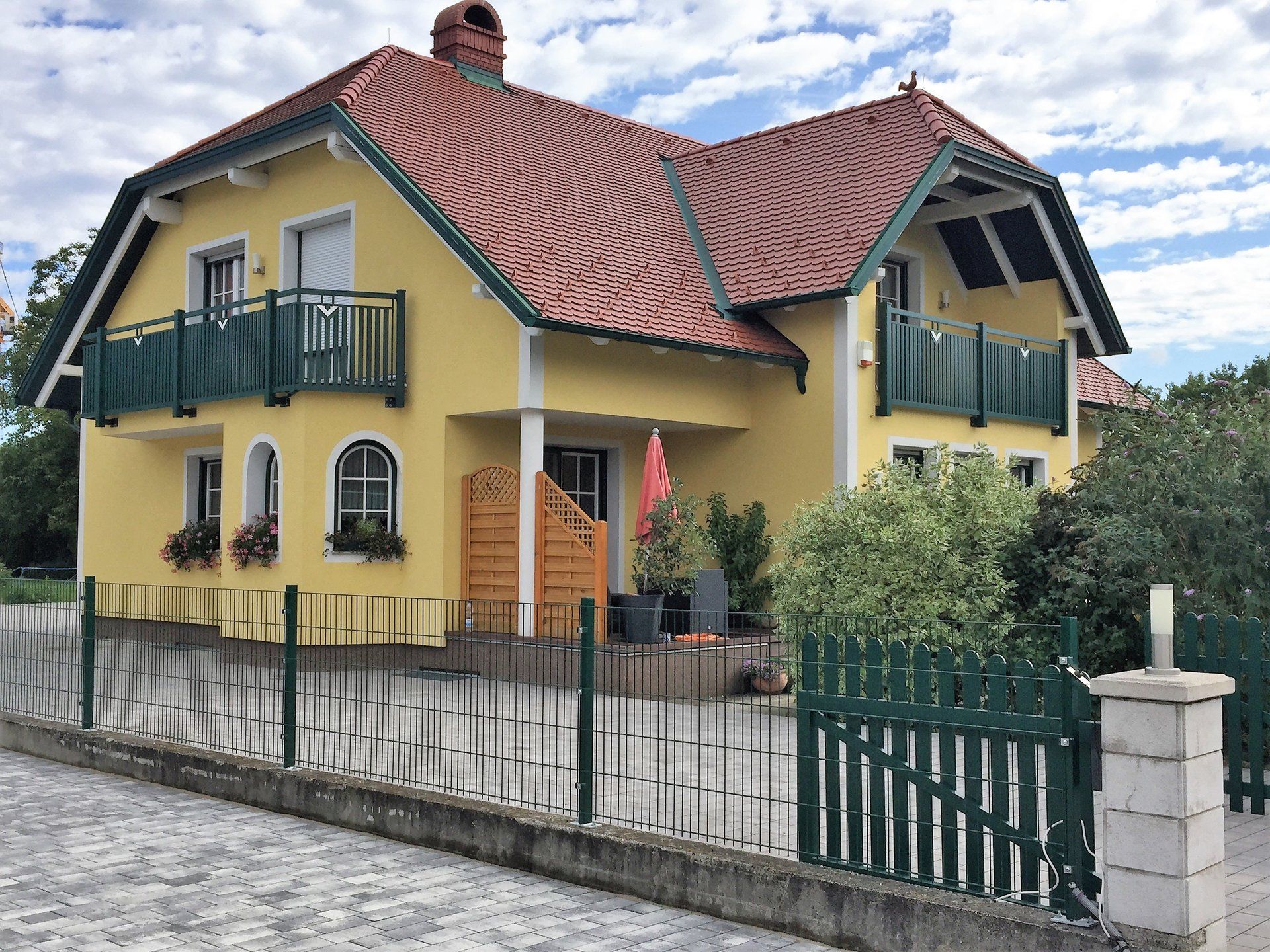 Ein gelbes Haus mit einem roten Ziegeldach und Balkonen