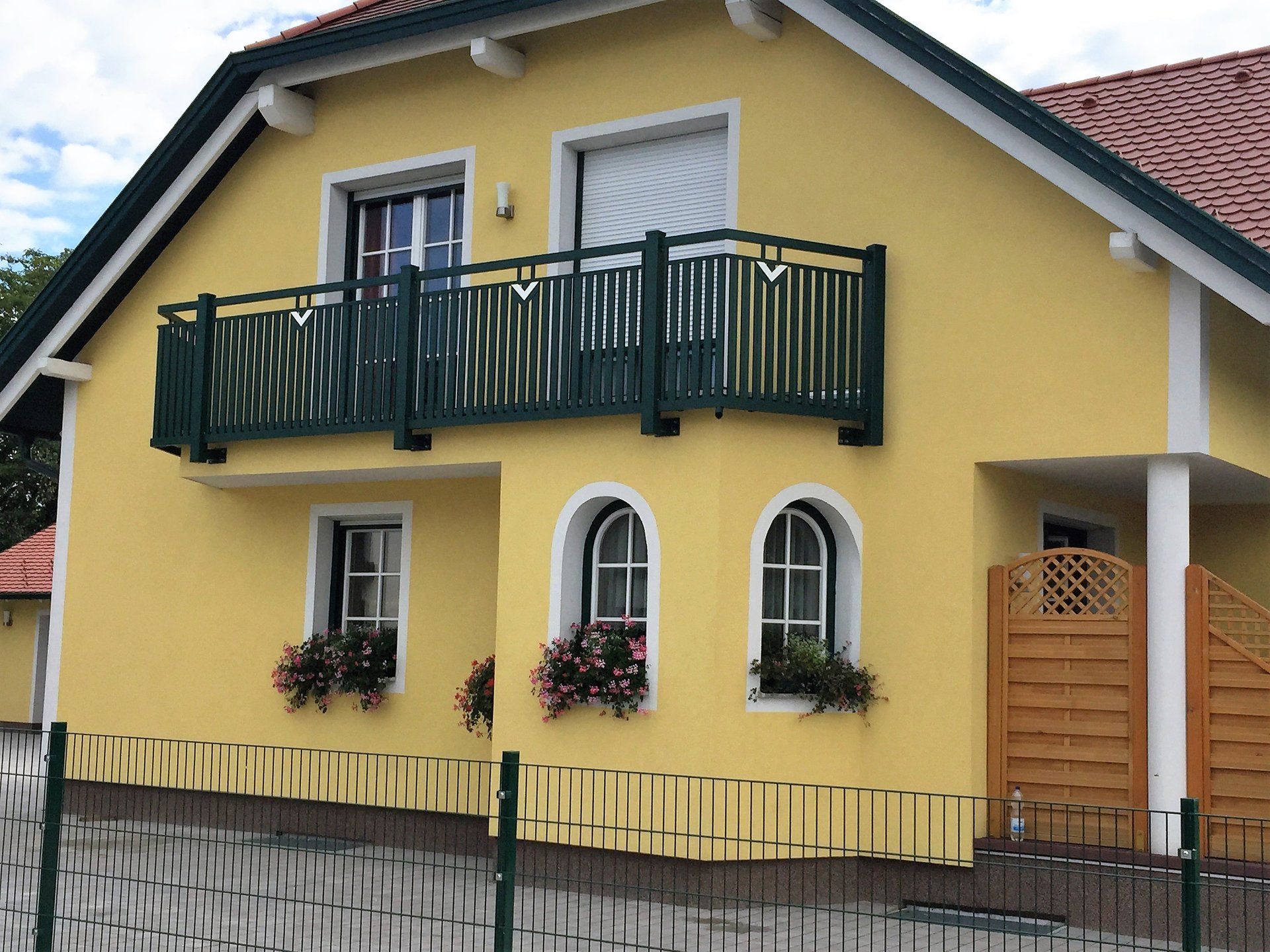 Ein gelbes Haus mit einem Balkon und einem Zaun darum