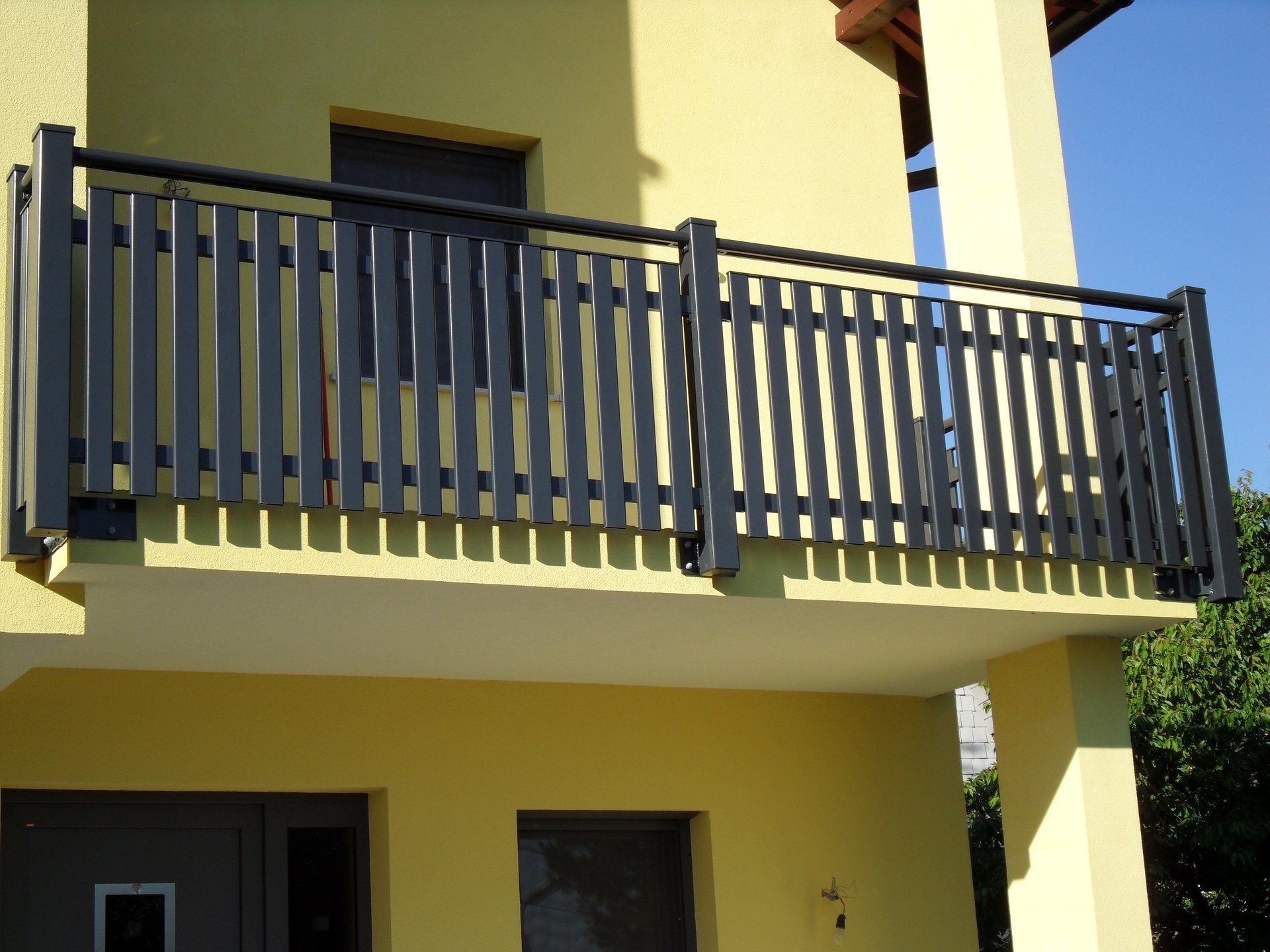 Ein gelbes Gebäude mit einem Balkon mit schwarzem Geländer