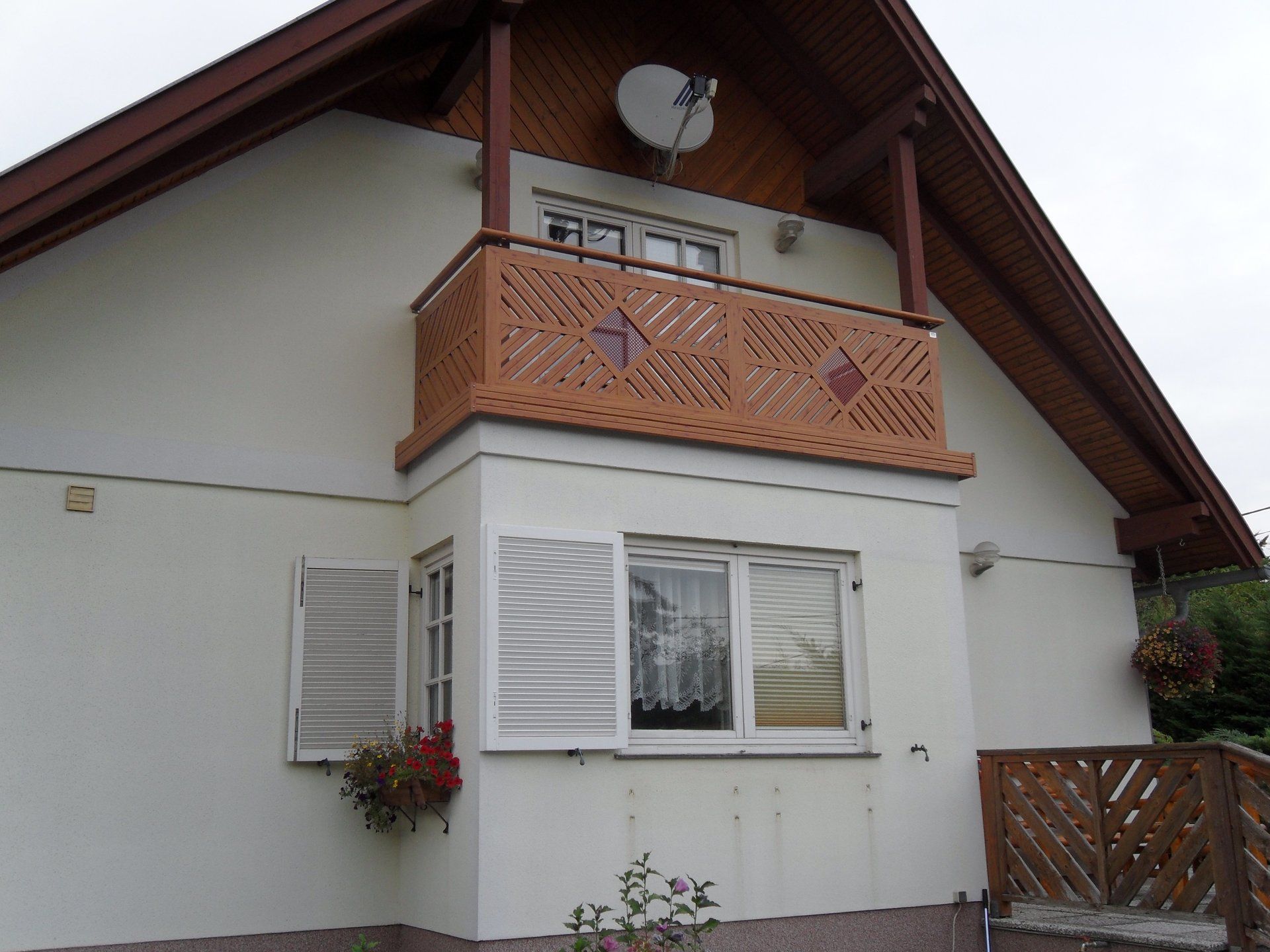 Ein weißes Haus mit einem Balkon und einer Satellitenschüssel auf dem Dach