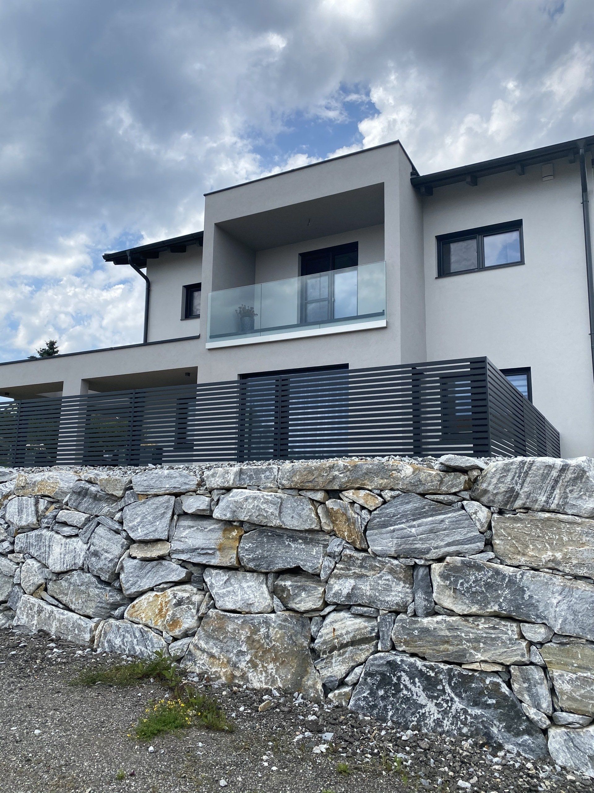 Ein großes Haus mit einer Steinmauer davor.