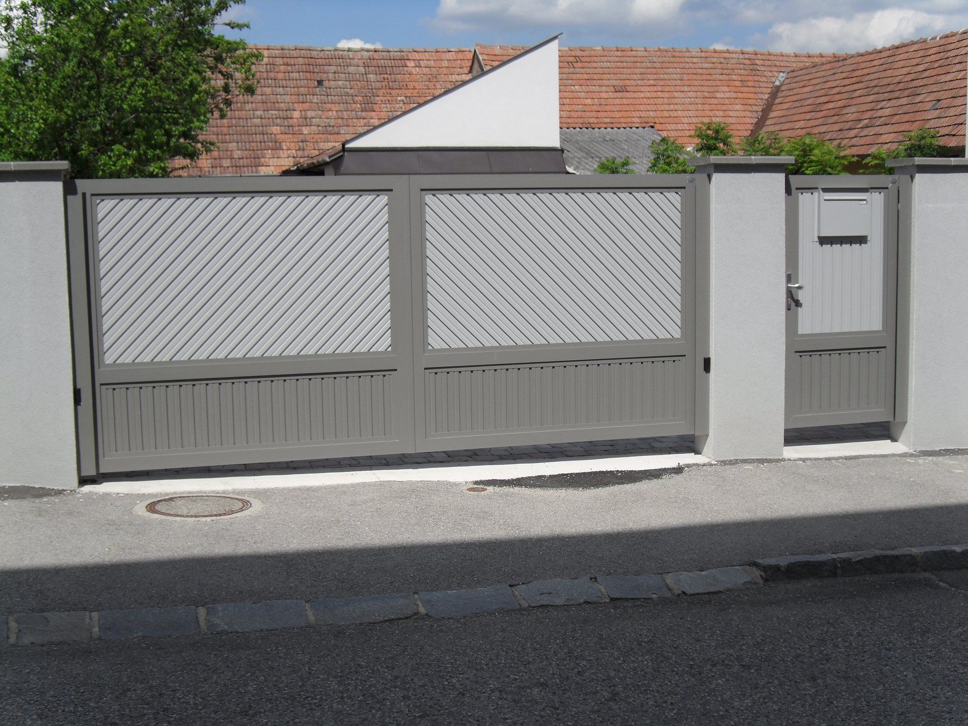 Ein Zaun mit einem Tor und einem Haus im Hintergrund