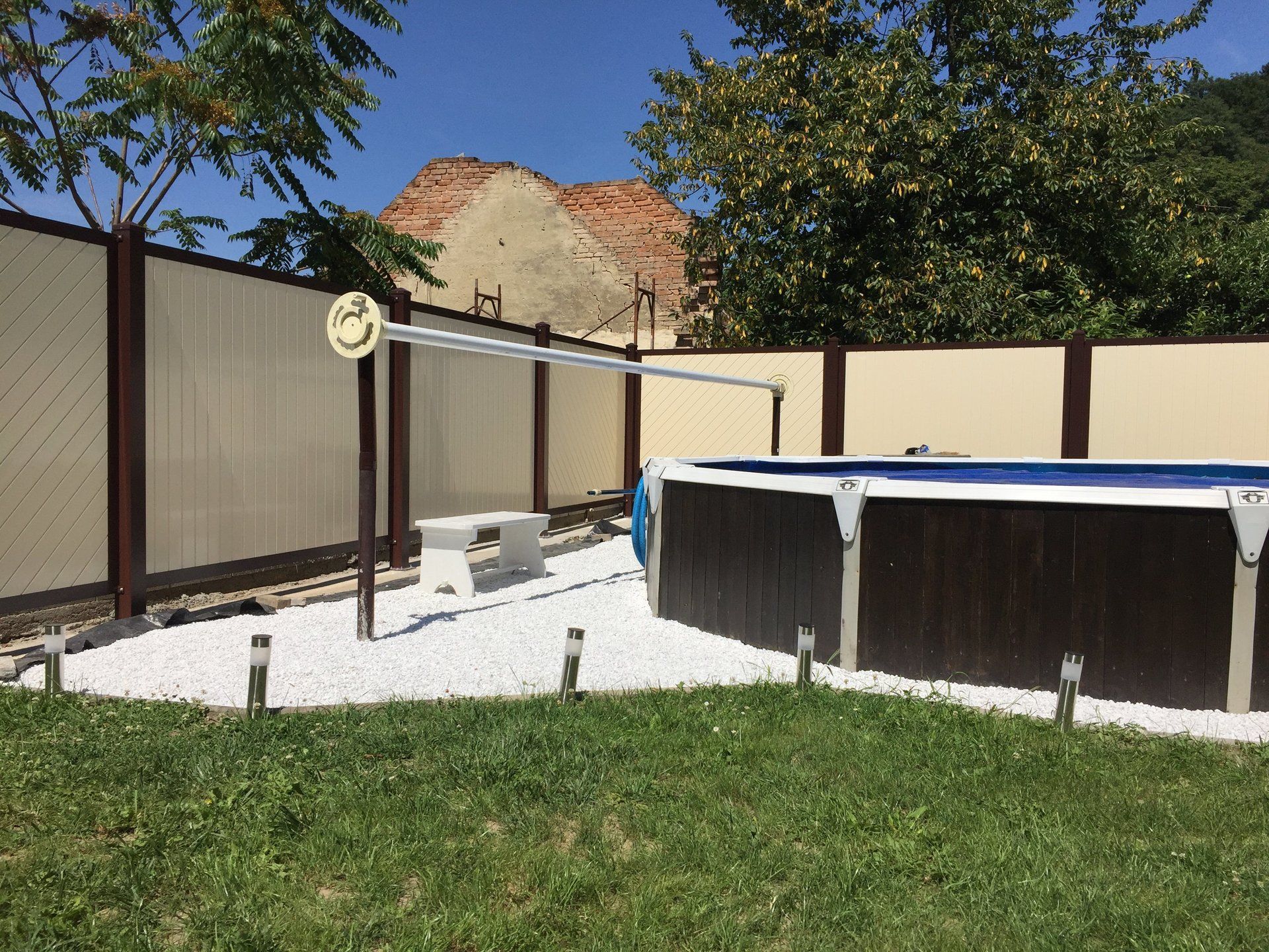 In einem Hinterhof ist ein Swimmingpool von einem Zaun umgeben.