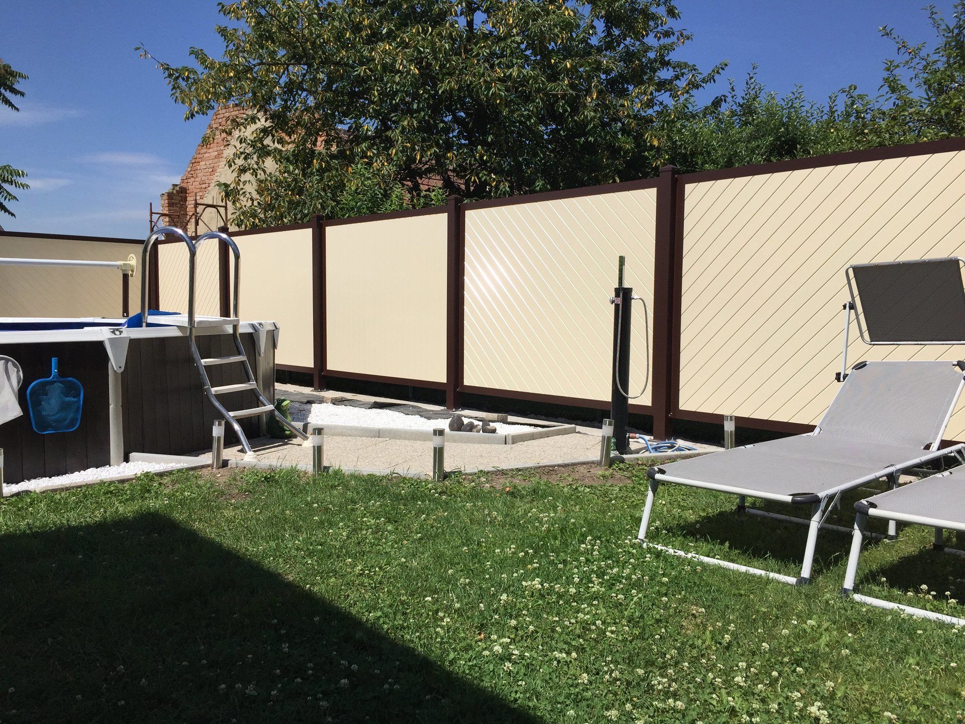 Ein Hinterhof mit Gartenstühlen und einem Pool hinter einem Zaun