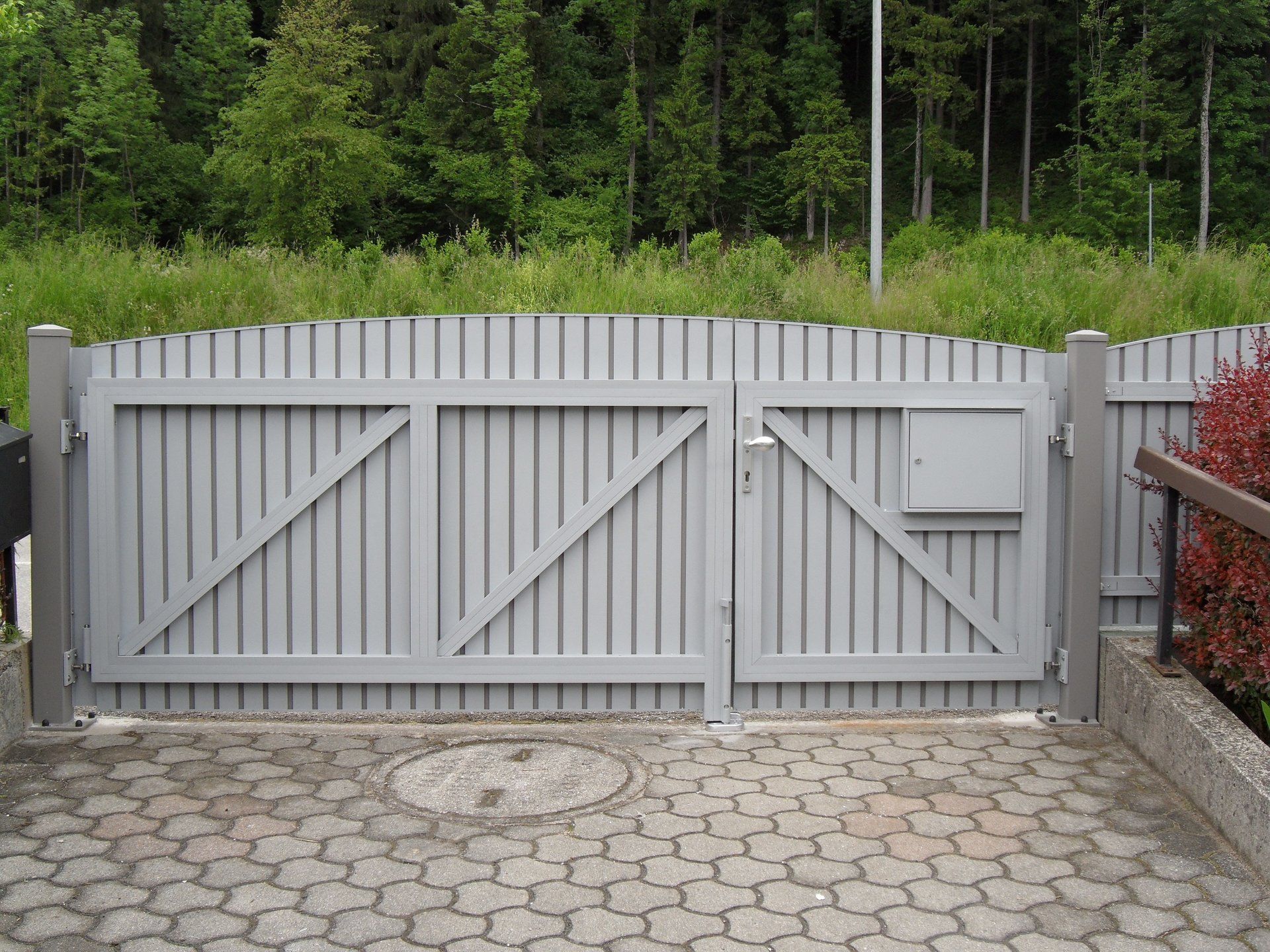 Ein graues Tor mit einem Briefkasten an der Seite