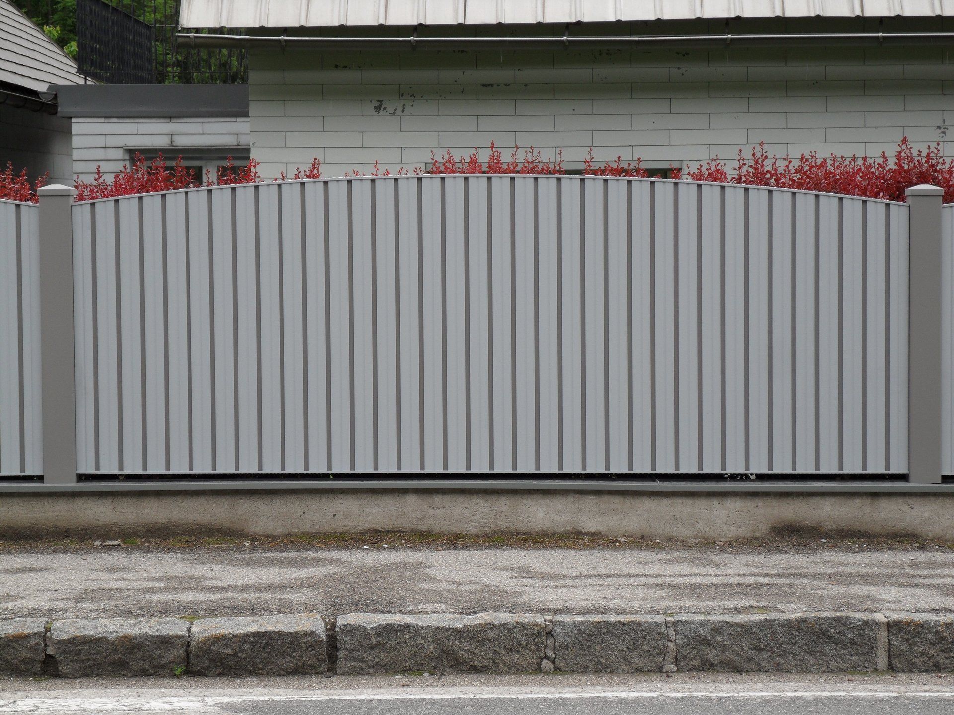 Ein weißer Holzzaun umgibt ein Haus am Straßenrand