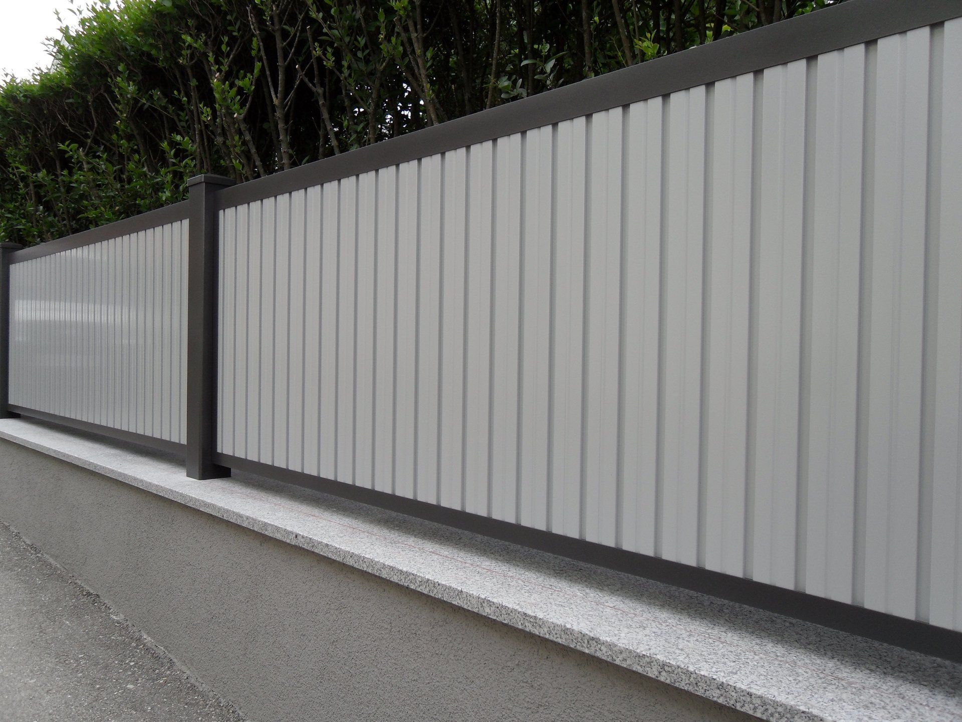 Am Straßenrand steht ein weiß-schwarzer Zaun.