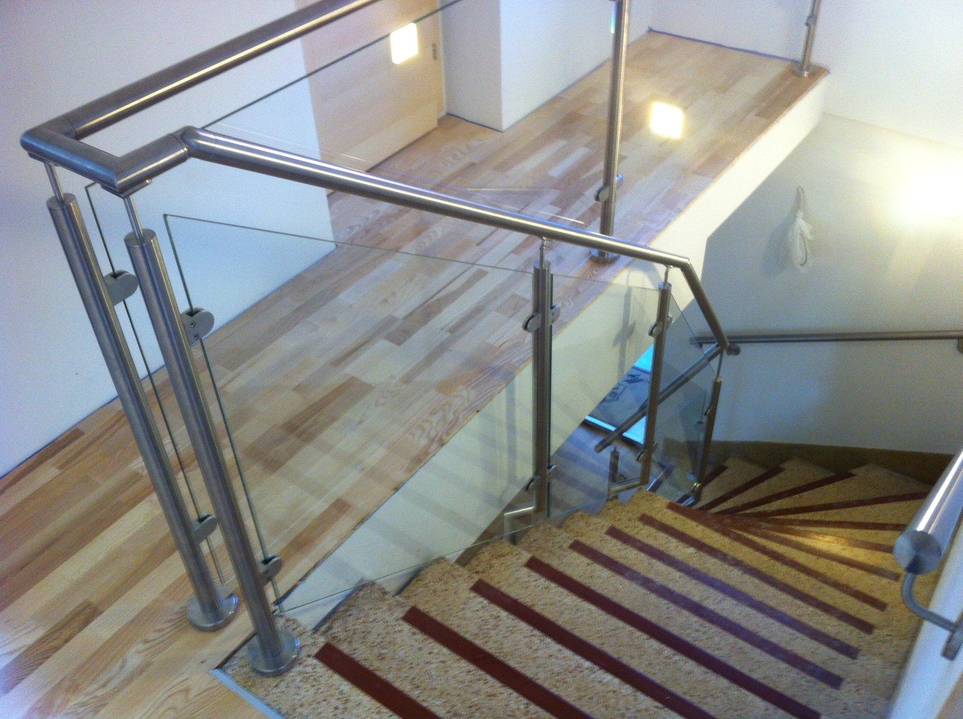 Eine Treppe mit Glasgeländer und Holzboden