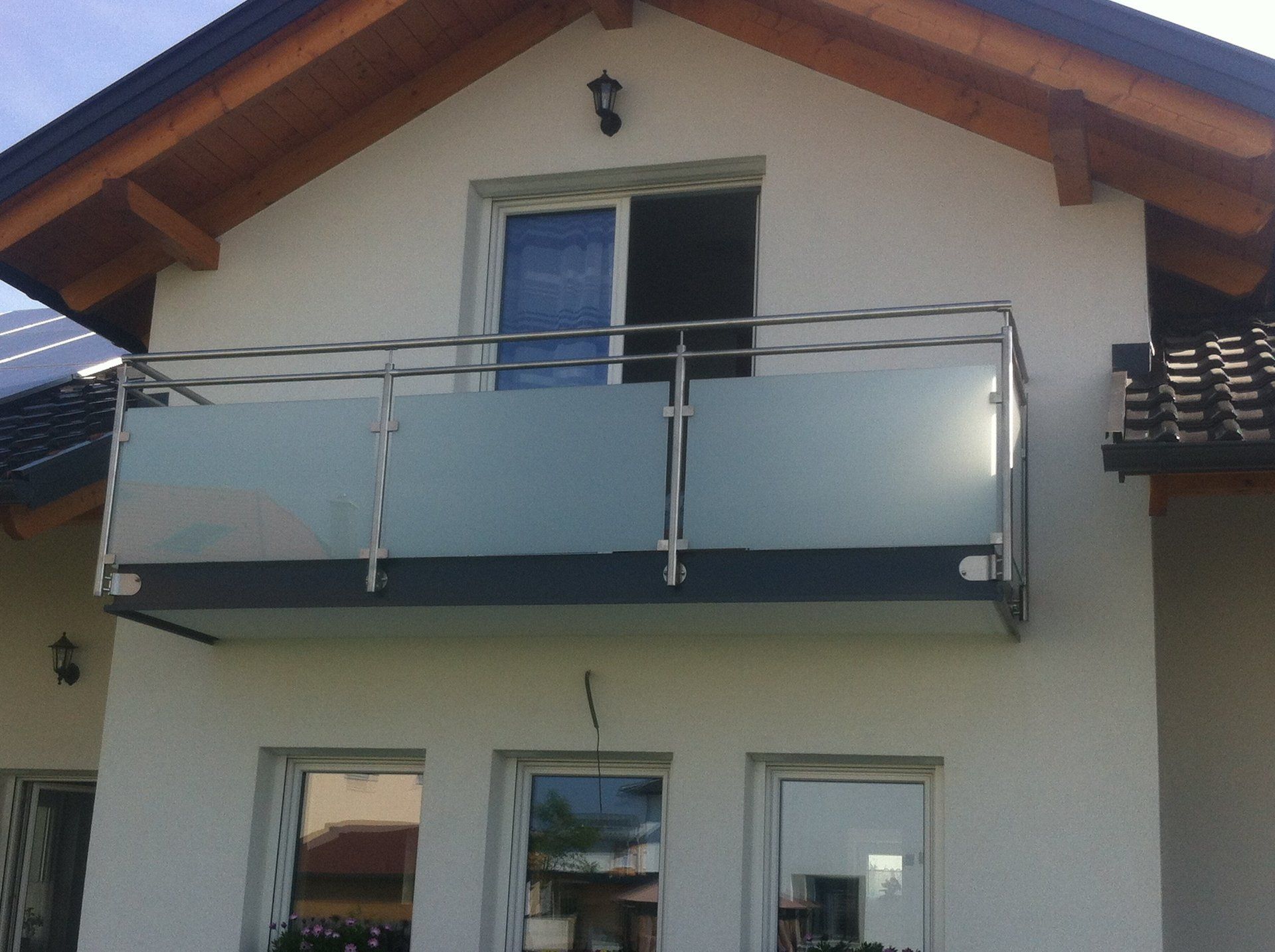 Ein weißes Haus mit Balkon und Edelstahlgeländer