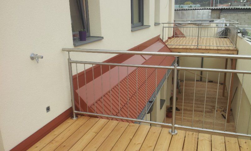 Ein Balkon mit Edelstahlgeländer und Holzterrasse