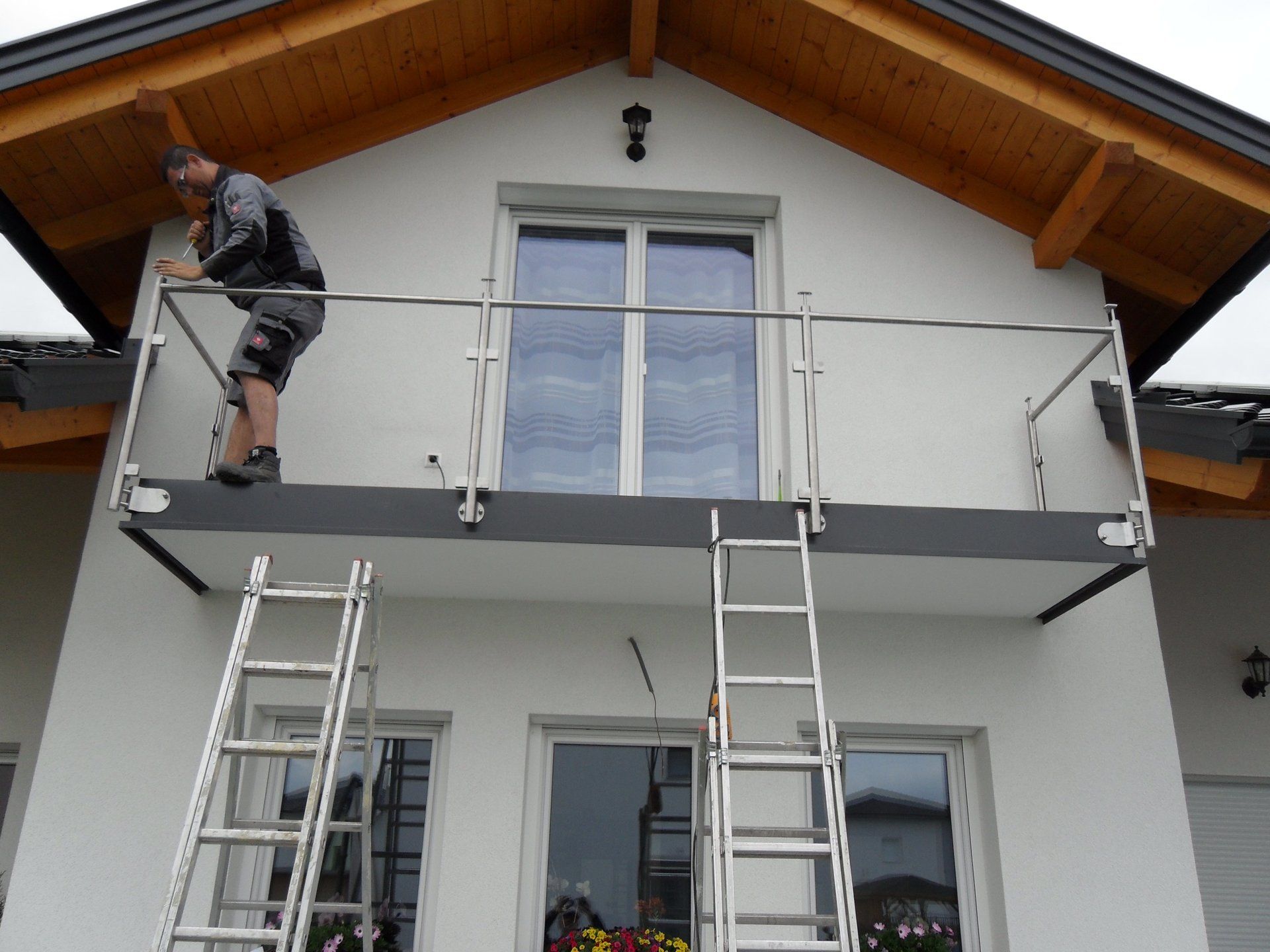 Ein Mann steht auf einem Balkon neben einer Leiter