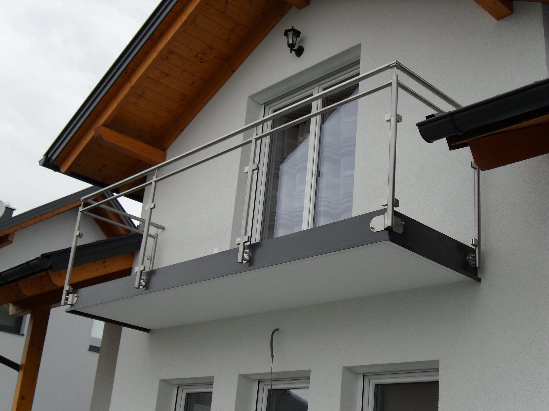 Ein weißes Haus mit einem Balkon mit einem Edelstahlgeländer