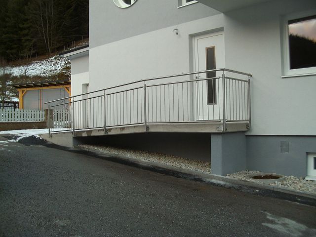 Ein weißes Haus mit einem Edelstahlgeländer und einer Rampe