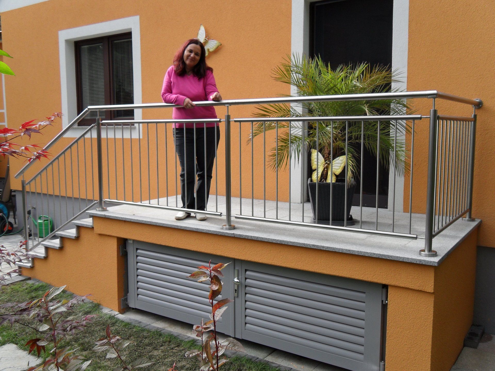 Eine Frau steht auf einem Balkon mit einem Edelstahlgeländer