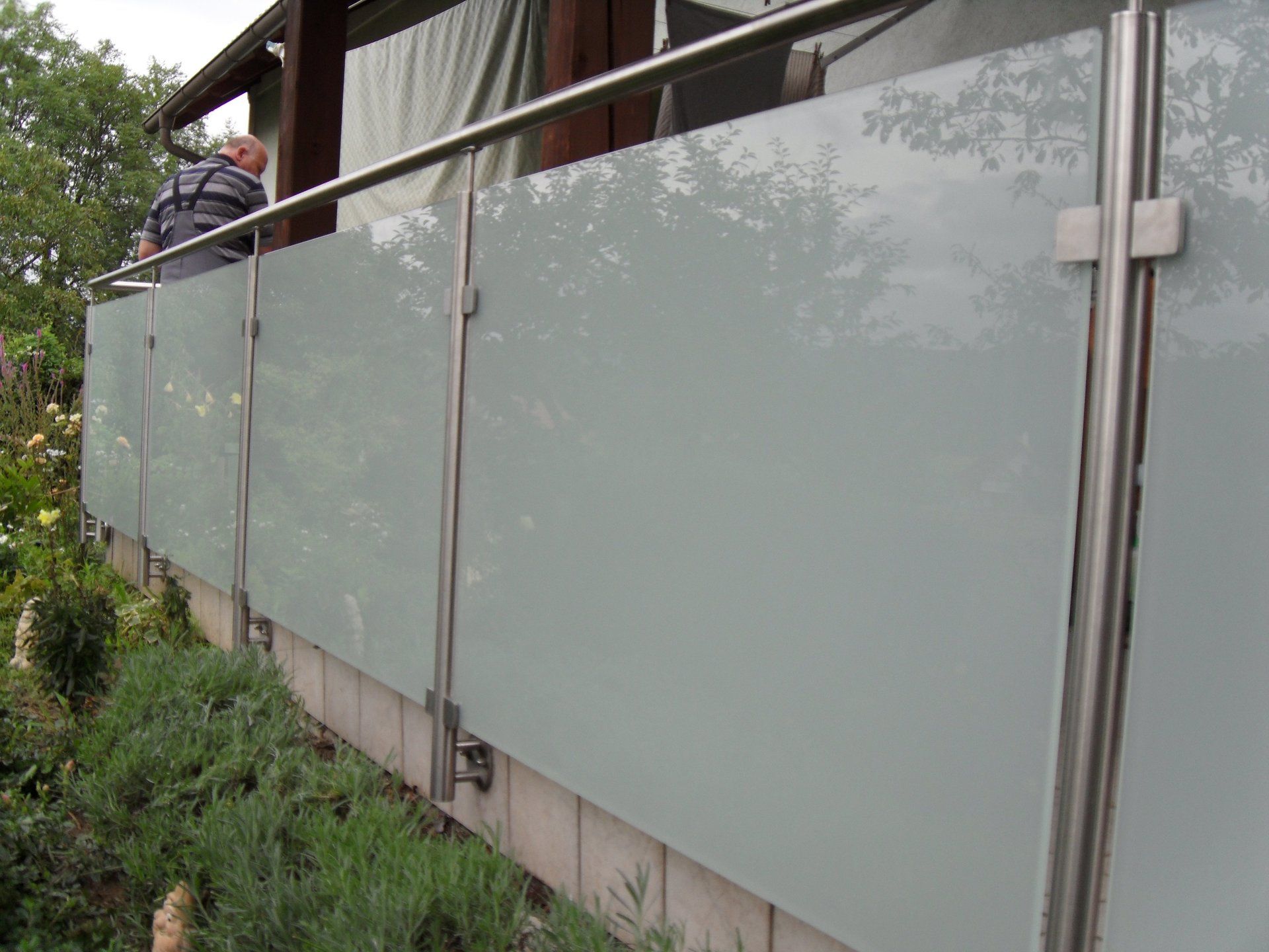 Ein Mann steht auf einem Balkon mit einem Edelstahlgeländer.