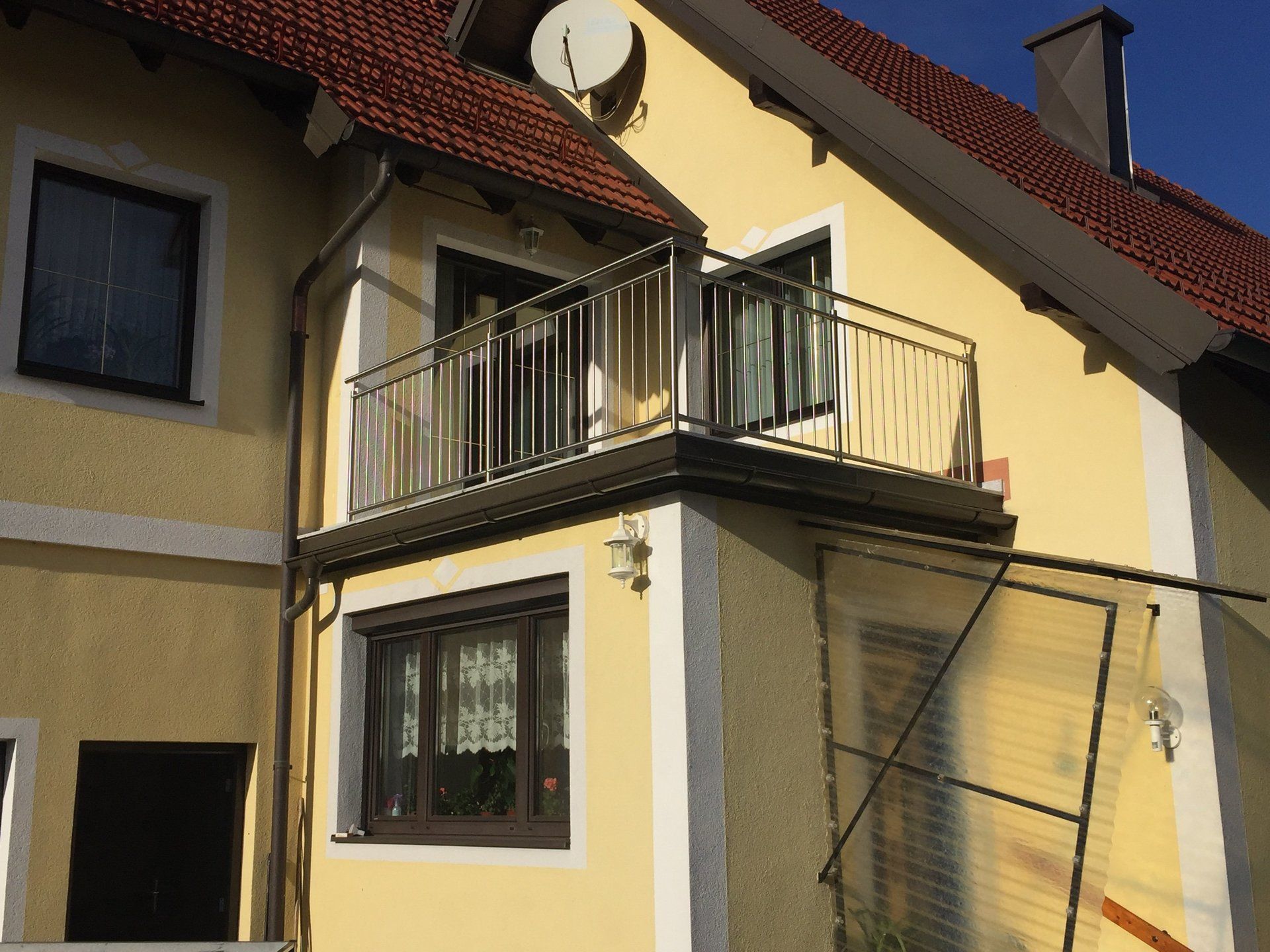 Ein gelbes Haus mit einem Balkon und einer Satellitenschüssel auf dem Dach