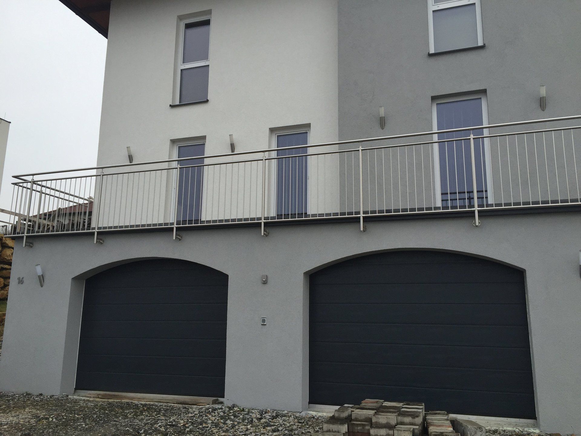 Ein Haus mit zwei Garagentoren und einem Balkon
